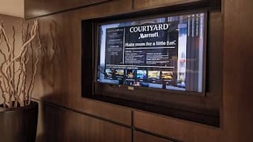 Un écran de télévision affiche le nom « Courtyard Marriott » accompagné du message : « Laissez place à un peu de divertissement. »