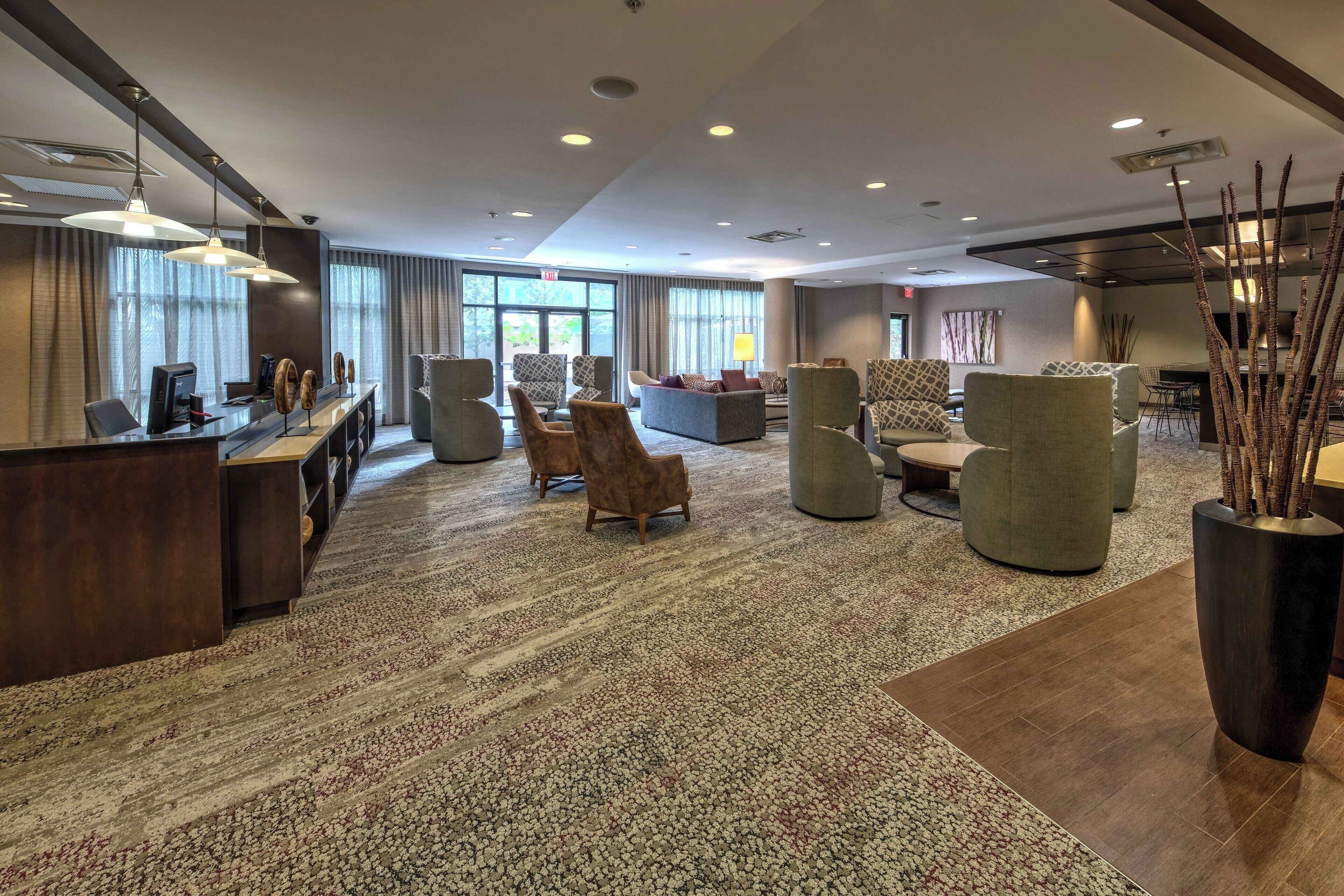 A spacious lobby with a reception desk, comfortable seating areas, and large windows providing natural light.
