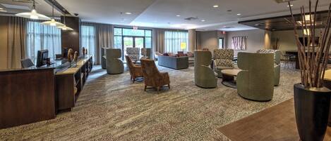 A spacious lobby with a reception desk, comfortable seating areas, and large windows providing natural light.