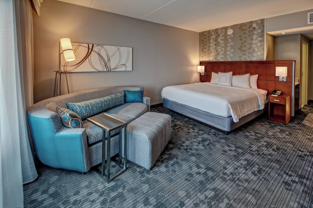Una habitación de hotel con una cama, un sofá, una mesita y una mesita de noche.