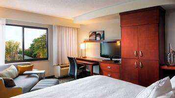 A hotel room with a bed, a desk with a computer, a TV, and a wardrobe.