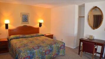 A hotel room with a bed, two bedside lamps, a desk, a chair, and a mirror.