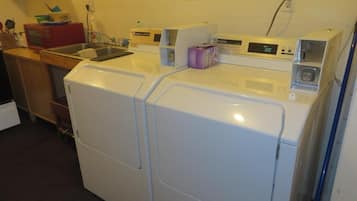 Zona de lavandería con lavadora y secadora de carga frontal, un lavabo y un microondas.