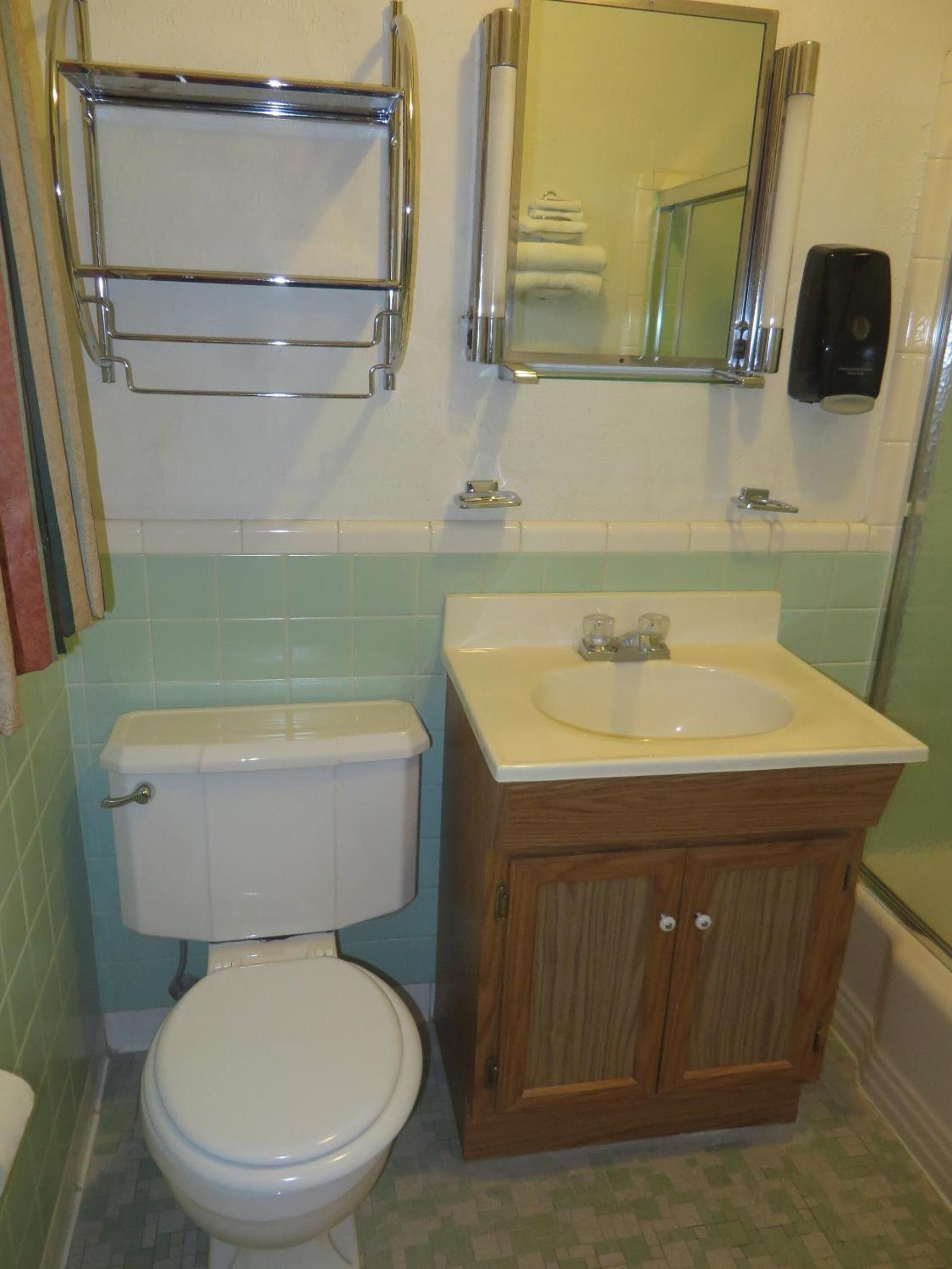 A bathroom with a toilet, sink, and mirror.