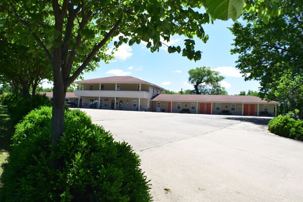 A two-story motel with a central parking area and a row of rooms with red doors. - Best Budget Inn (Carthage)