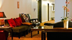 A cozy living room with a sofa, armchairs, a coffee table, and a bookshelf. - The Hotel 91 (New York)