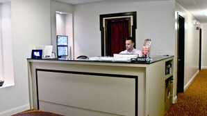 A reception desk with a computer, a monitor, and a sign indicating no smoking. - The Hotel 91 (New York)