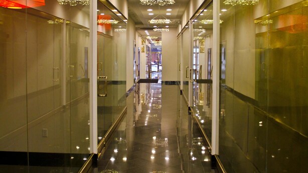 A modern corridor with reflective floors, glass walls, and recessed lighting. - The Hotel 91 (New York)