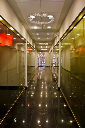 Een moderne gang met reflecterende vloeren, glazen wanden en inbouwverlichting.