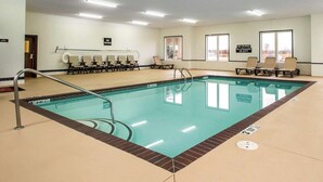 Una piscina interior con un cartel de prohibido bucear, sillas de descanso y un letrero que indica servicio de salvavidas.