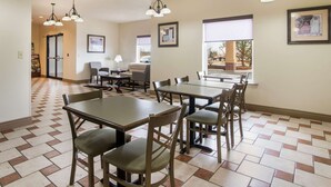 Un comedor con varias mesas y sillas, un piso con estampado de cuadros y luces en el techo.