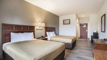 A hotel room with two beds, a desk, and a chair.
