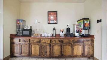 A kitchen area with a coffee station, microwave, toaster, and various appliances.