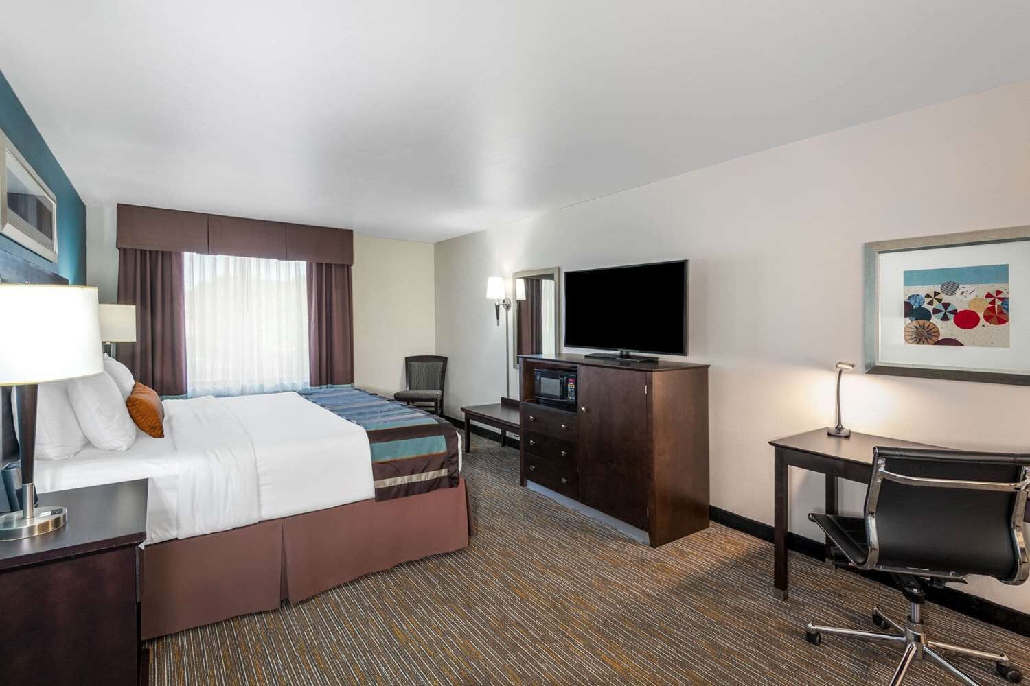 A hotel room with a bed, a desk, a television, and a chair.