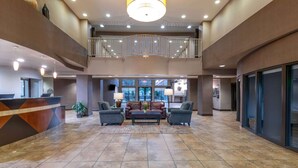 A spacious lobby with a reception desk, seating area, and a balcony. - Wingate by Wyndham St. George (St. George)