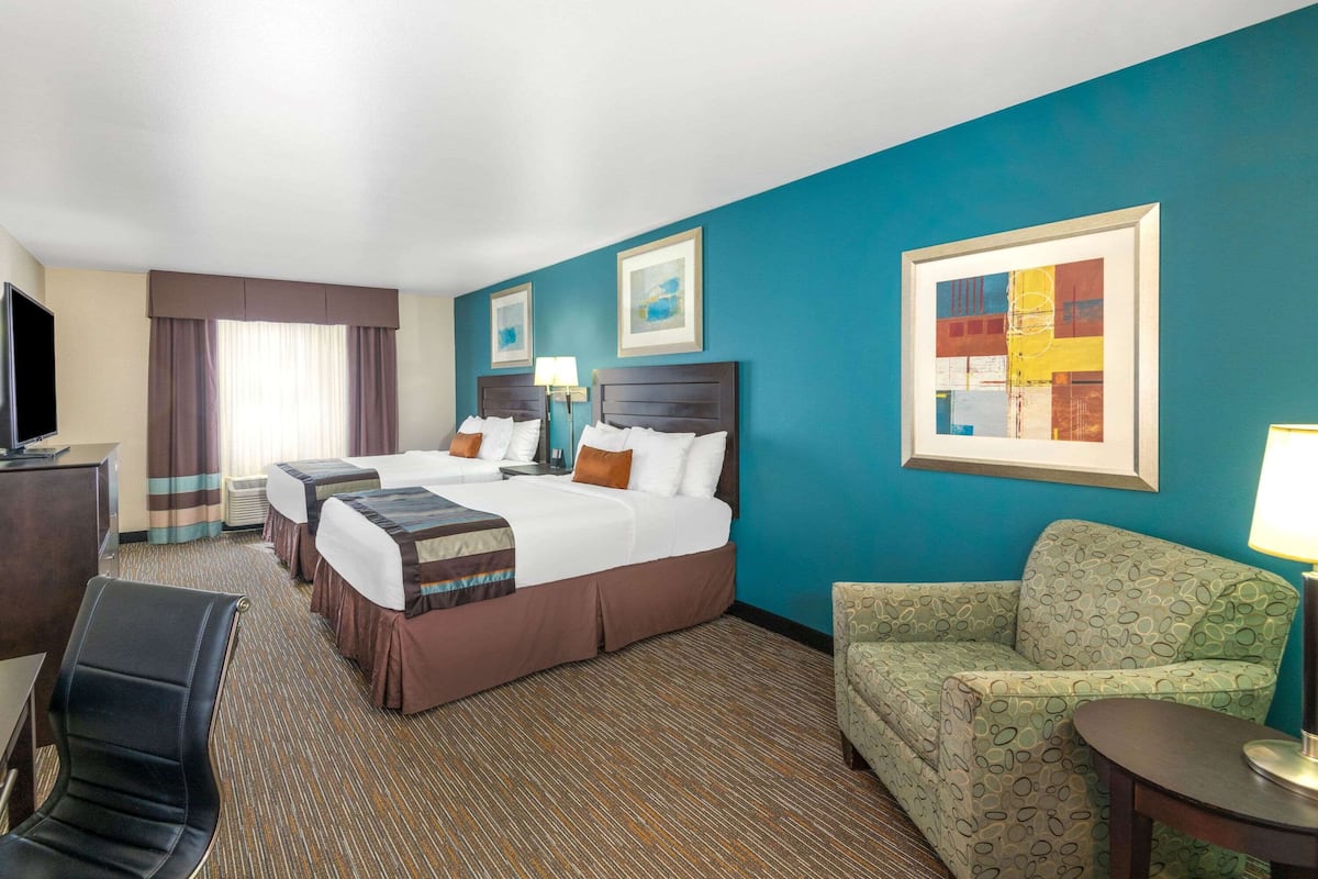 A hotel room with a large bed, two bedside tables, a TV, a sofa, and a desk.