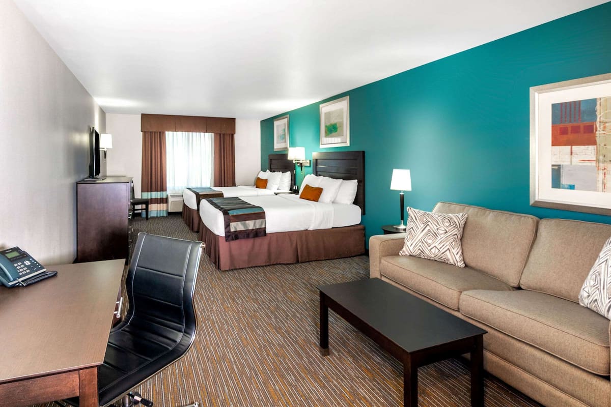 A hotel room with two beds, a sofa, a desk, and a telephone.