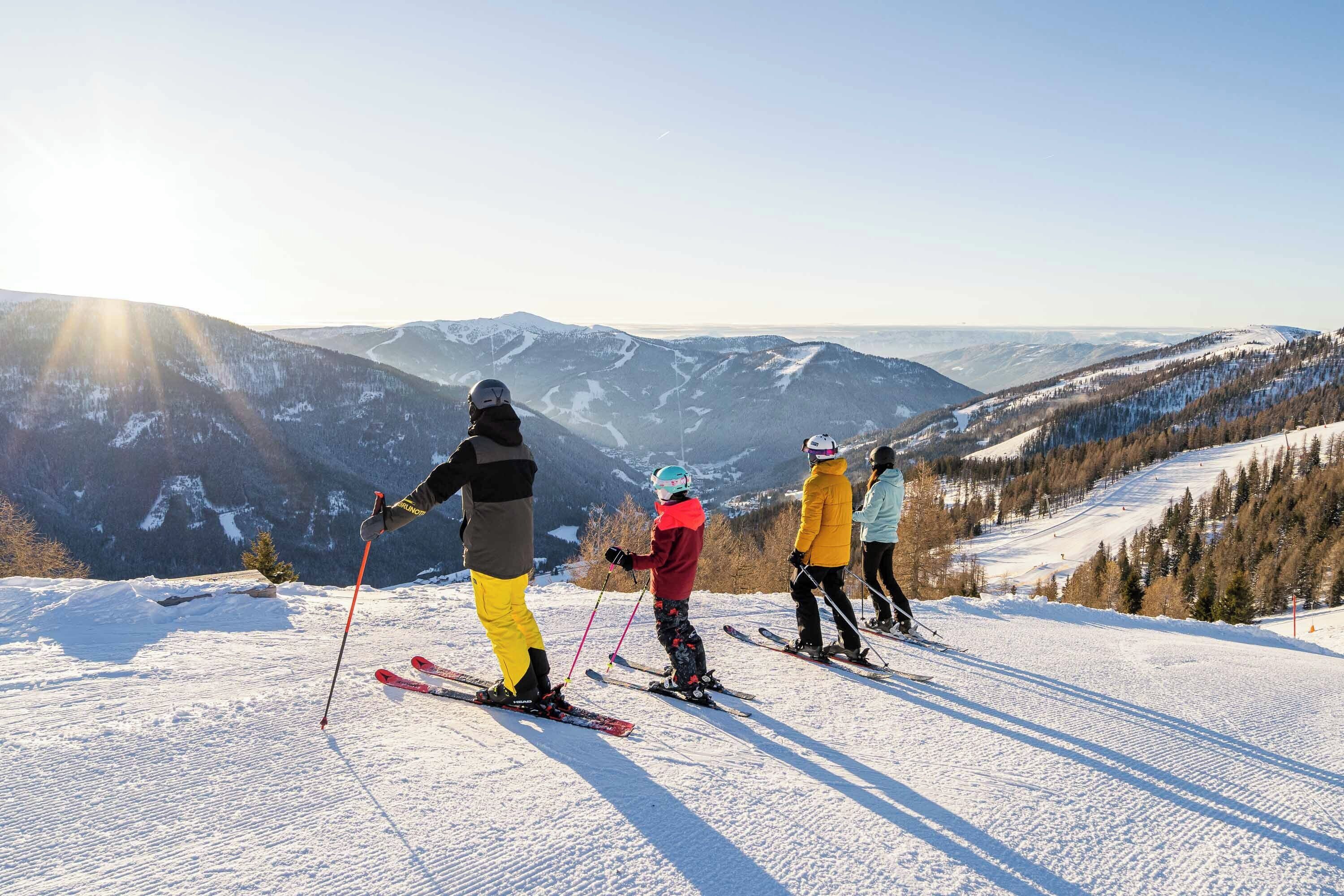 A group of skiers on a snowy slope with a mountainous backdrop.