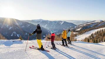 A group of skiers on a snowy slope with a mountainous backdrop.