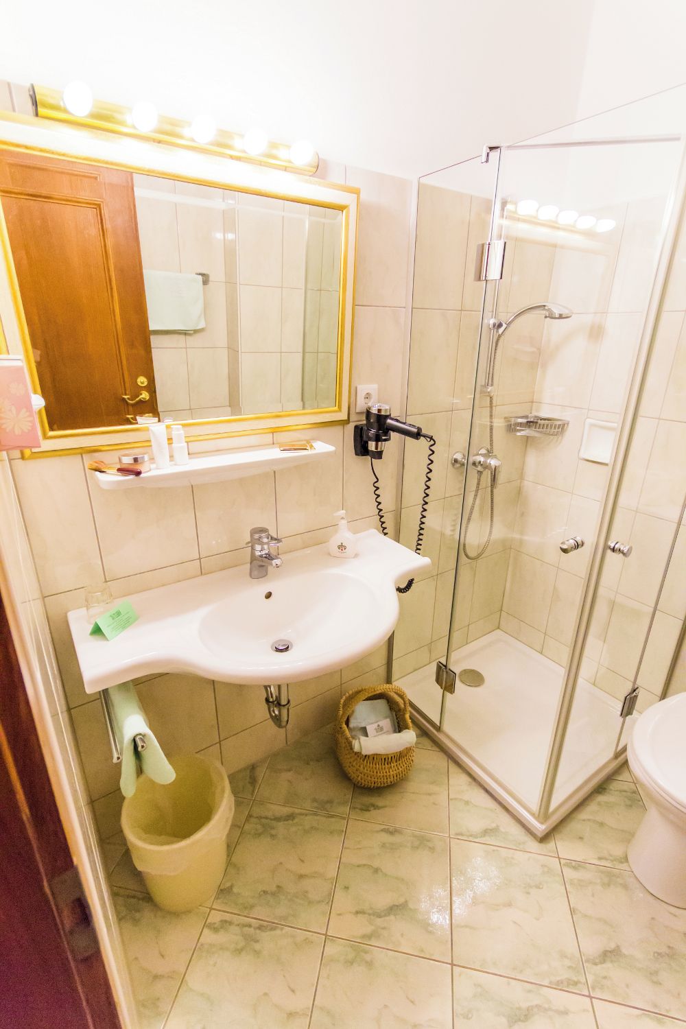 A bathroom with a white sink, a mirror, a glass-enclosed shower, and a toilet.