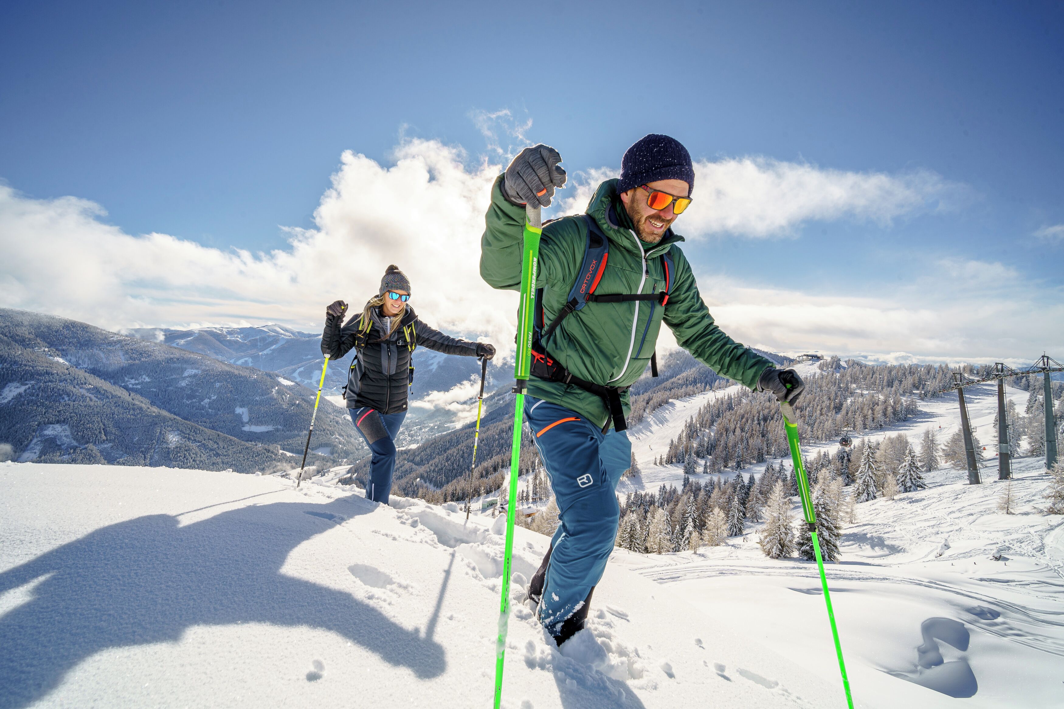 Dos personas esquiando en una montaña nevada bajo un cielo despejado.