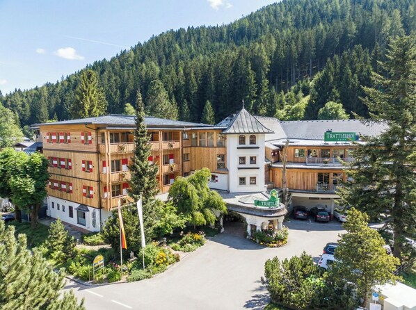 Een hotel met meerdere verdiepingen en een centrale binnenplaats, omringd door een dicht bos.