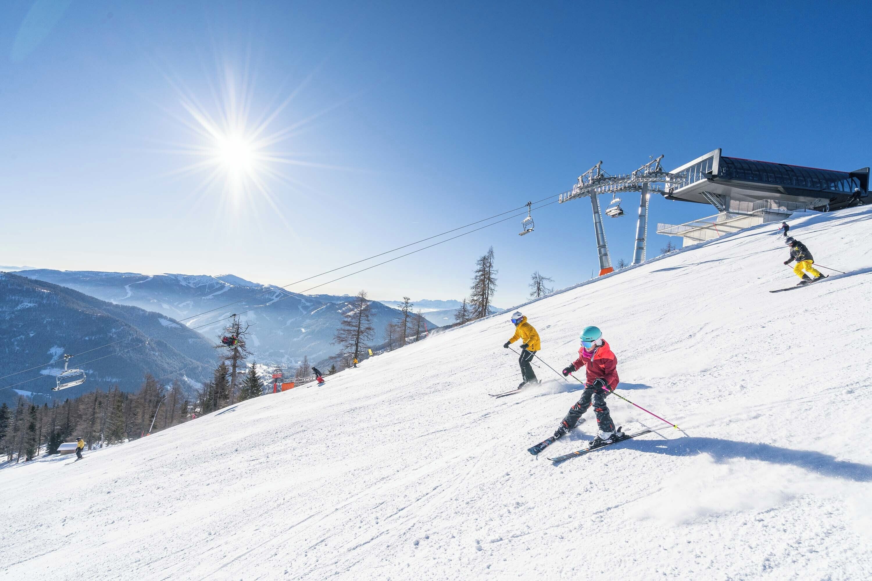 A ski slope with skiers, a ski lift, and a clear sky.