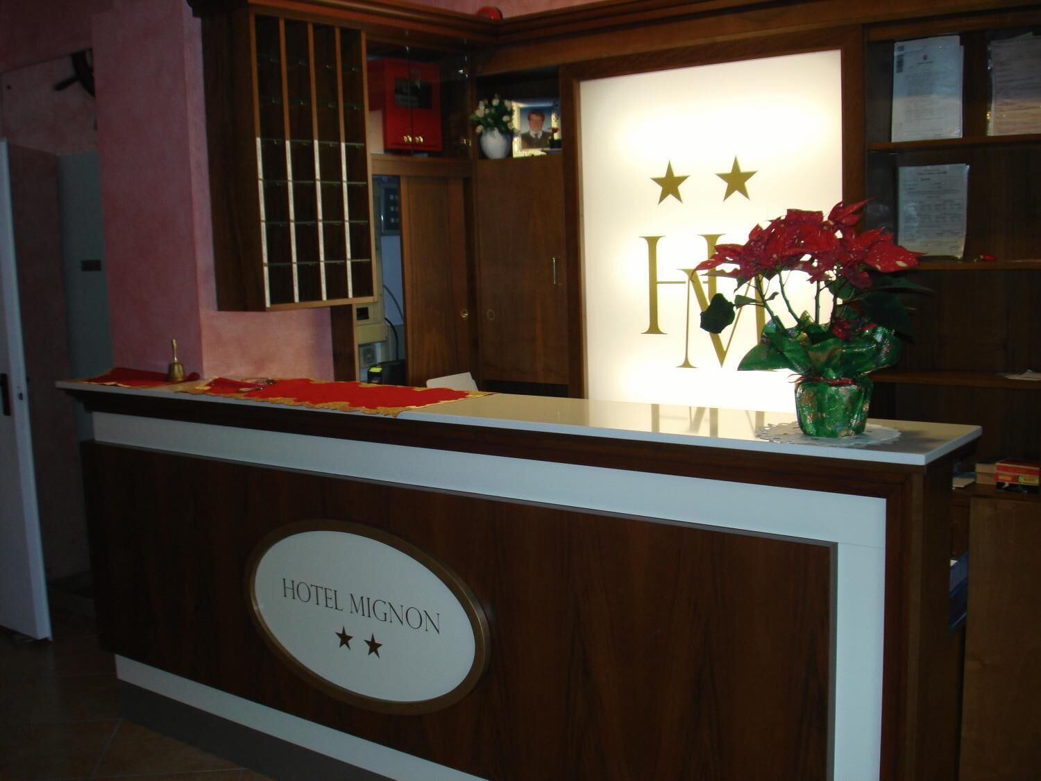 Una reception di hotel con un cartello che riporta 'HOTEL MIGNON' e una pianta decorativa.
