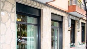 A building with large windows and a stone facade. There are potted plants on the windowsill. - Hotel Mignon (Alassio)