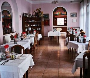 A restaurant with multiple tables, each covered with a white tablecloth, and chairs arranged around them. - Hotel Mignon (Alassio)