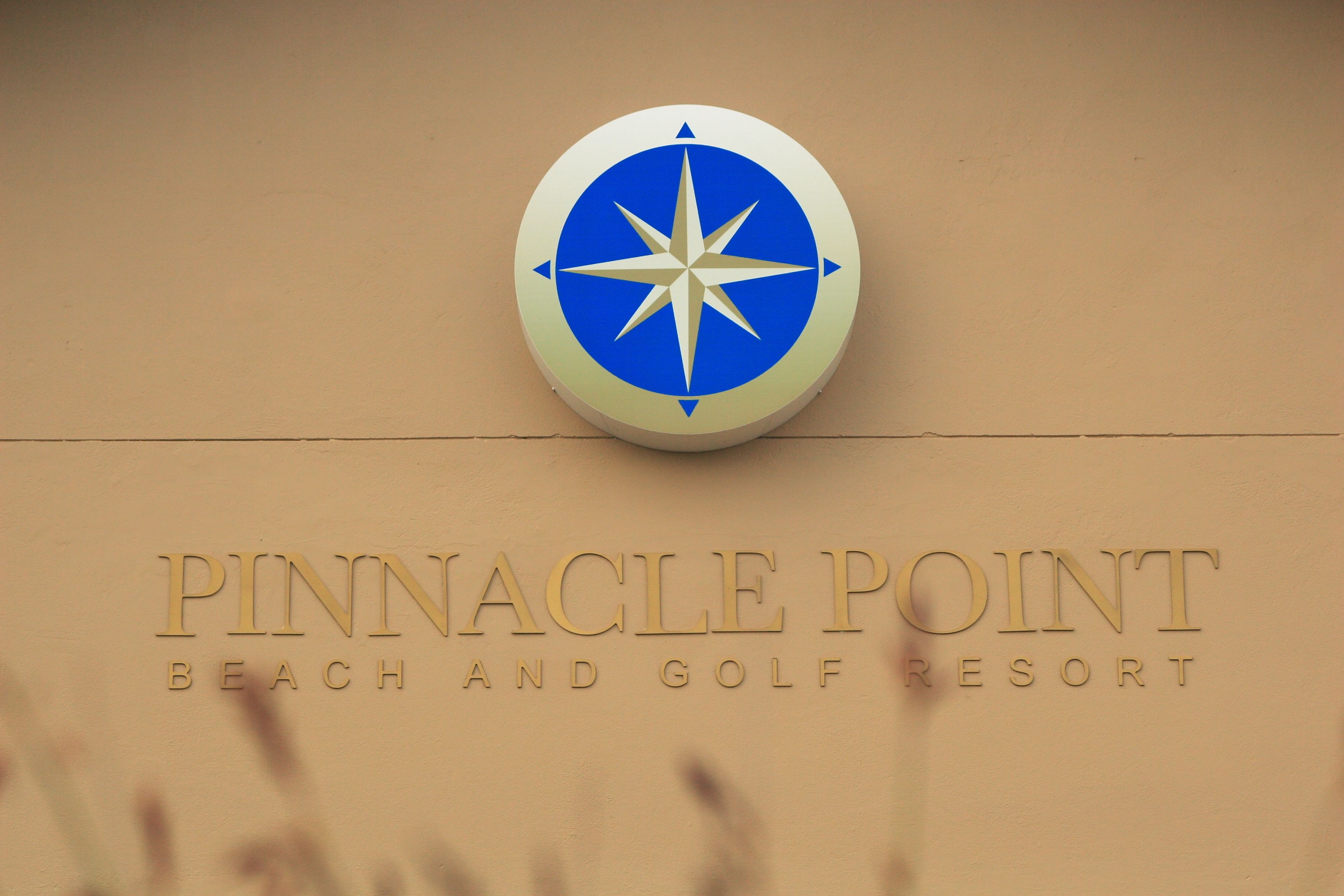 Señal para Pinnacle Point Beach and Golf Resort con un logotipo de brújula.