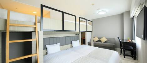 A hotel room with a large bed, a desk, a chair, and a sofa.