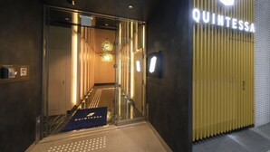 L’entrée d’un hôtel, avec une porte en verre, un tapis bleu portant le nom de l’hôtel et une enseigne au-dessus de la porte.