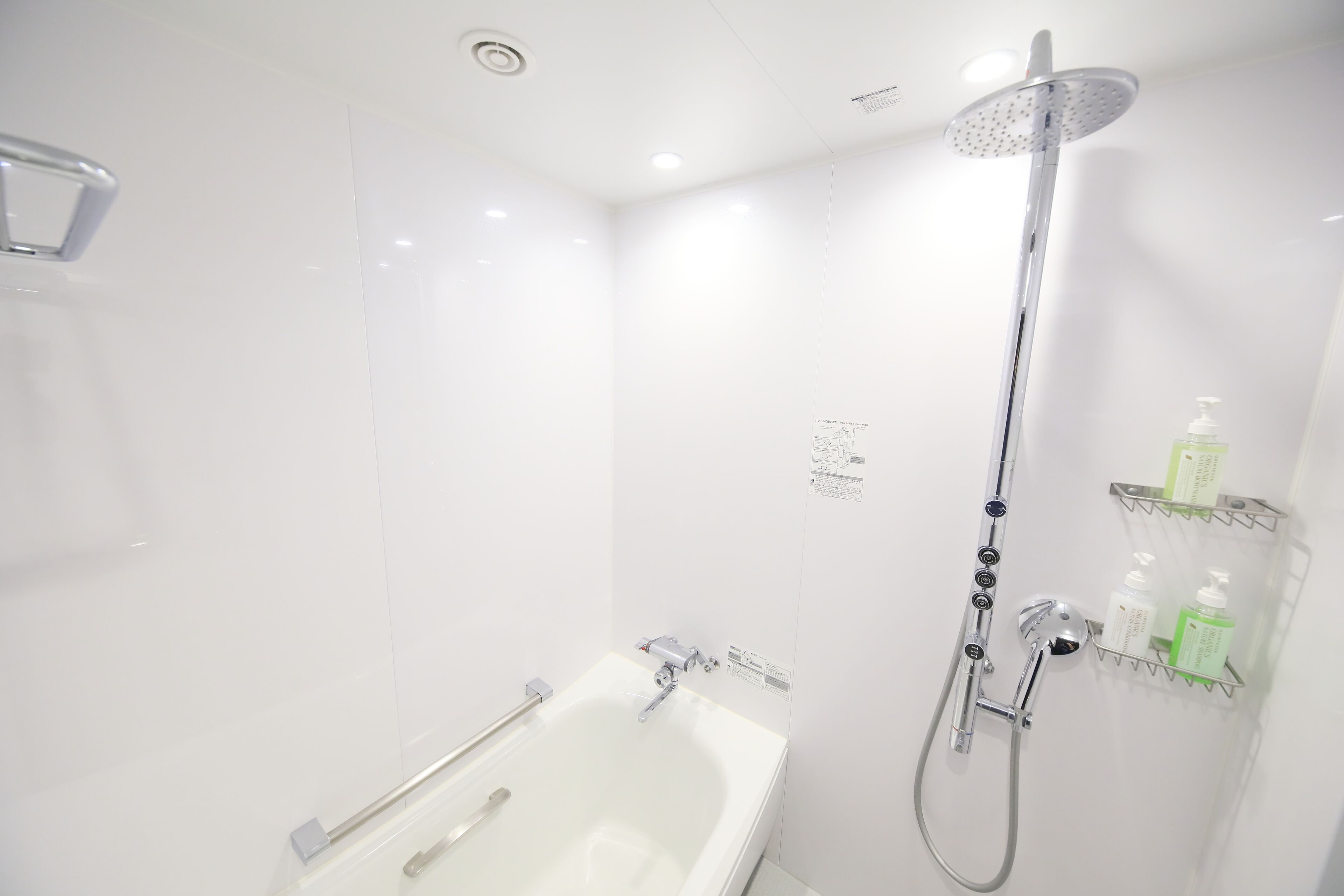 A modern bathroom with a bathtub, shower, and built-in shelves for toiletries.