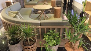 Un espace de détente moderne avec un canapé incurvé, des tables rondes et des plantes en pot.