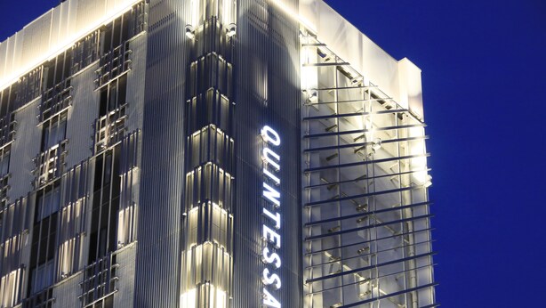 Un bâtiment moderne doté d’une façade en verre réfléchissant et sur lequel le nom « QUINTESSA » est clairement affiché.