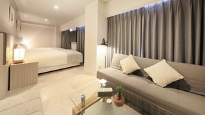 Une chambre d’hôtel moderne avec un lit, un canapé et une table basse en verre.