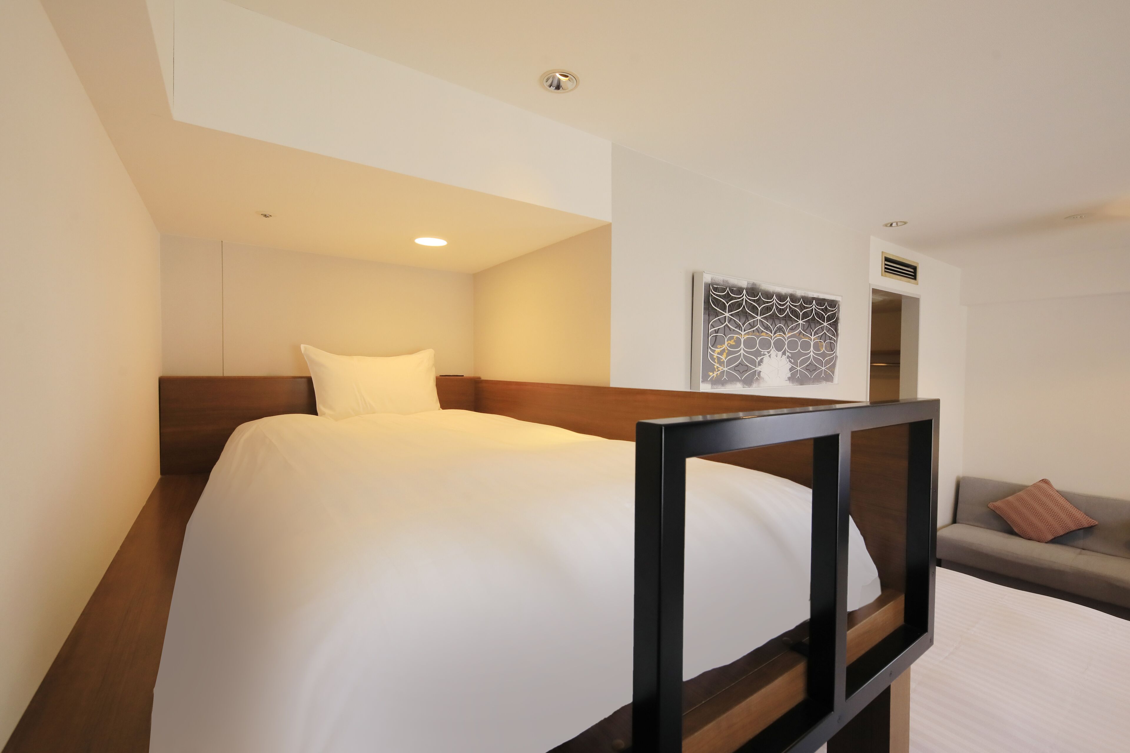 Ein Hotelzimmer mit einem Bett, einem Sofa und einem an der Wand hängenden Kunstwerk.