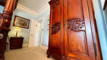 A hallway with a large wooden wardrobe, a door, a lamp, and a framed picture on the wall.