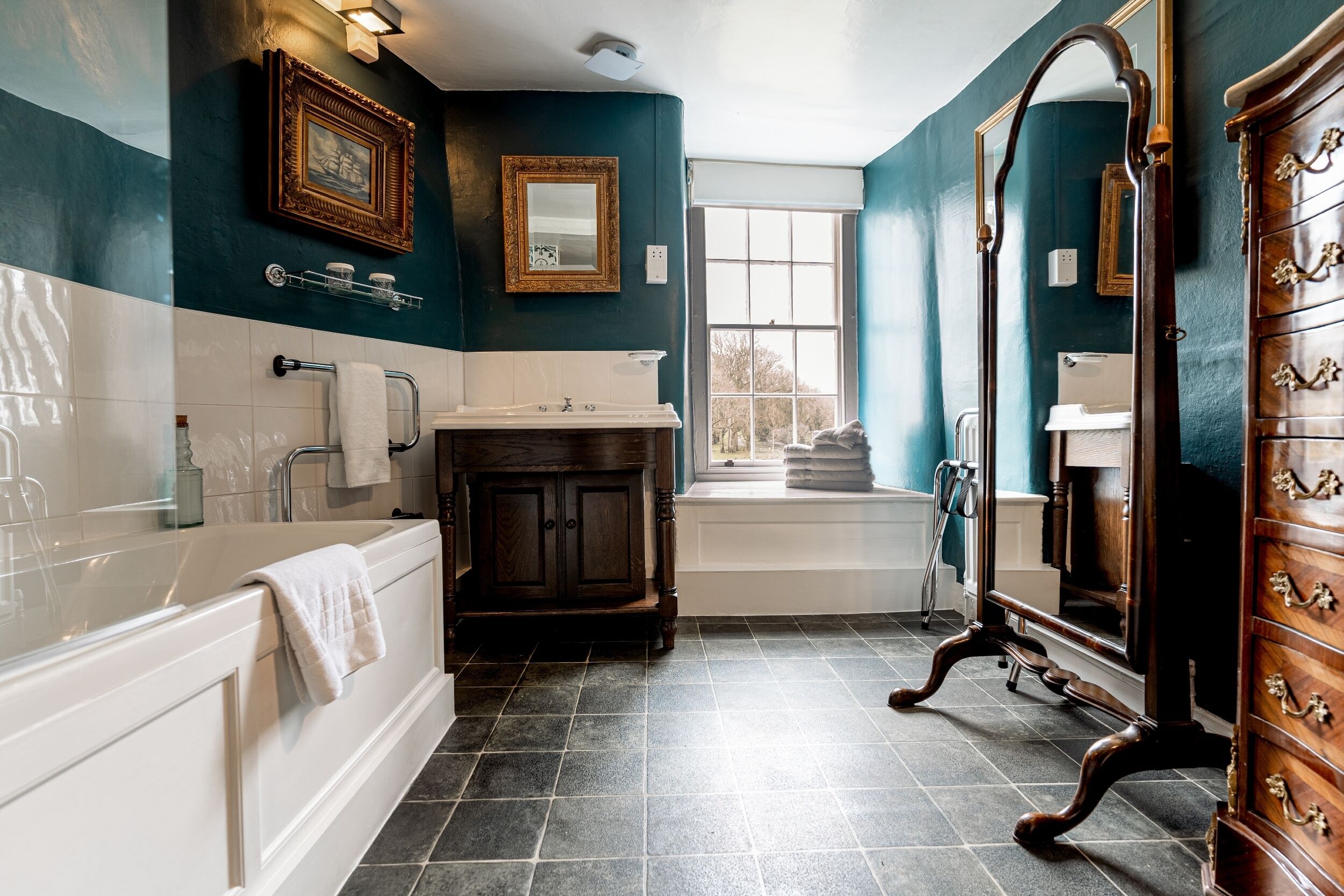 A bathroom with a bathtub, vanity, and a large mirror.