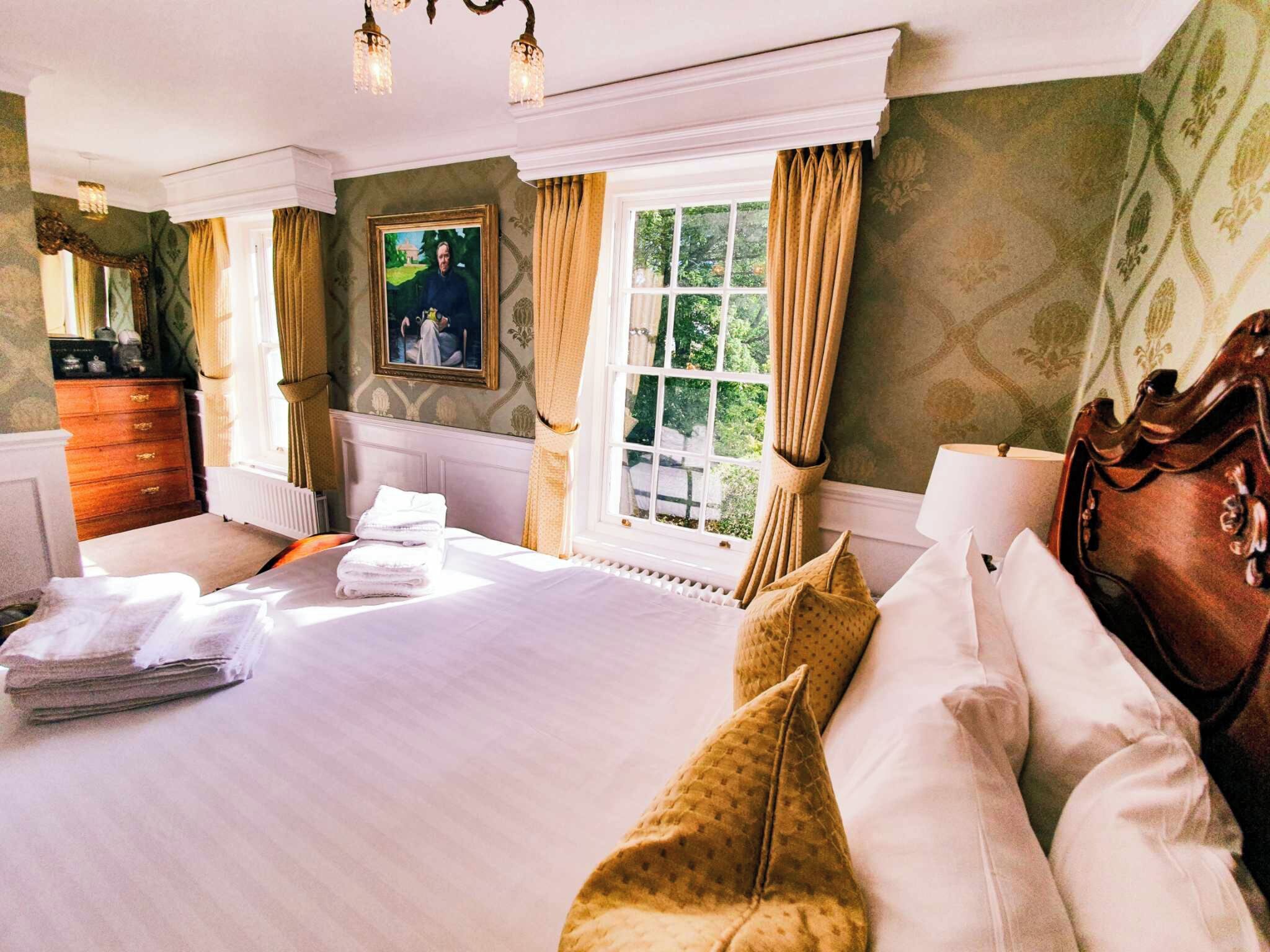 A well-appointed bedroom with a large bed, a dresser, and a window with curtains.