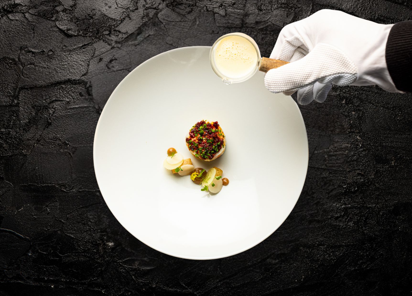 A white plate with a dessert and a hand holding a spoon.