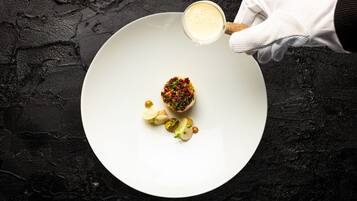 A white plate with a dessert and a hand holding a spoon.