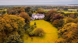 A large estate with a prominent house surrounded by lush greenery and fields. - Plas Dinas Country House (Caernarfon)