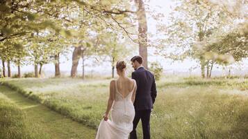 A couple walking in a grassy area with trees.