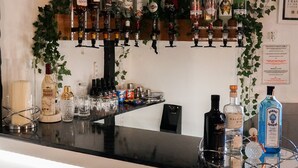 A bar area with shelves of liquor bottles, glasses, and a few chairs. - The Sandpiper Guest House (Torquay)