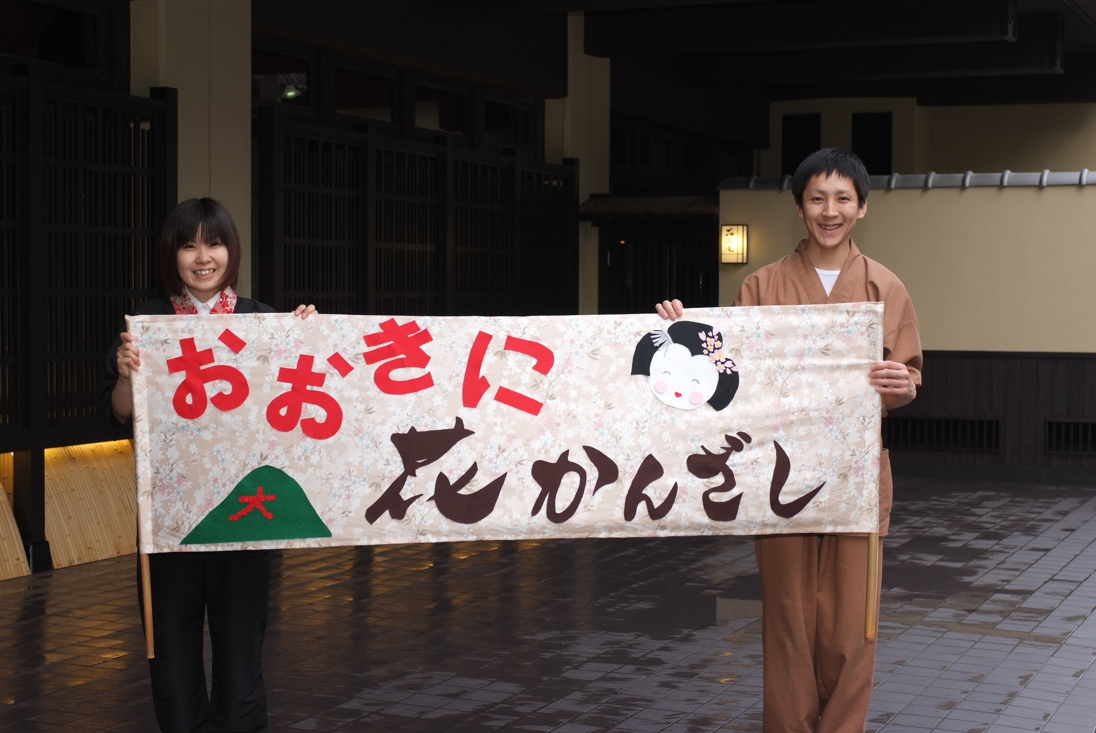 Deux personnes tenant une banderole avec du texte en japonais et un personnage de dessin animé.