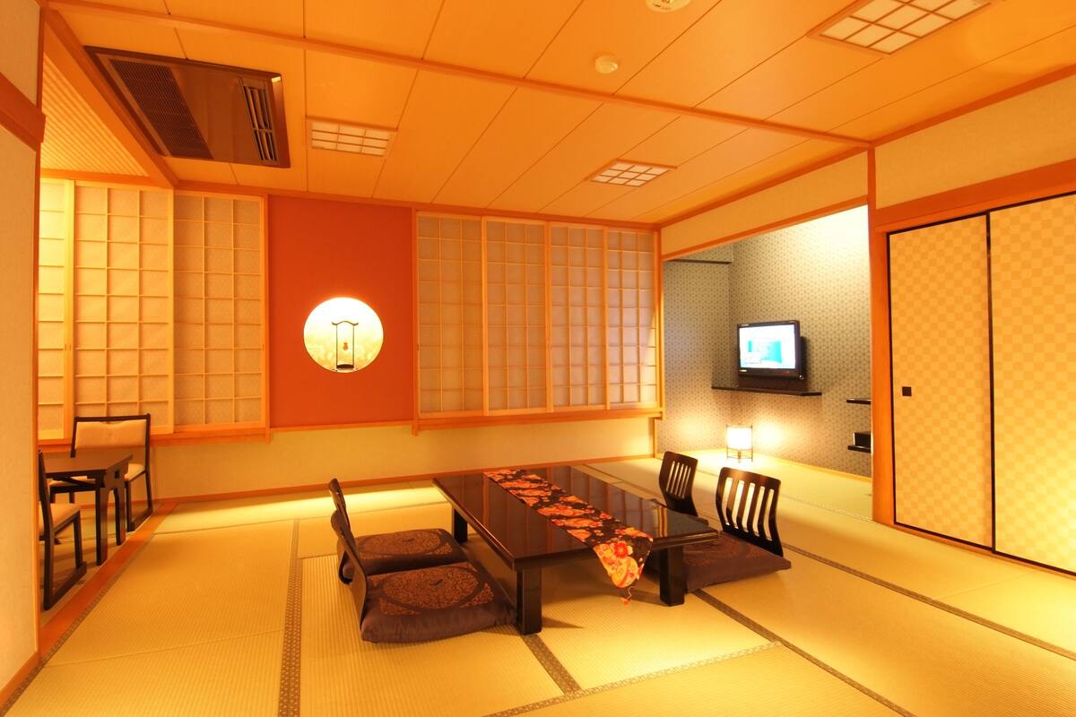 A traditional Japanese-style room with tatami flooring, a low table with cushions, and sliding doors.