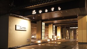 Een hotelgevel in traditionele Japanse bouwstijl, met een betegeld dak en een bord met verlichte tekens.