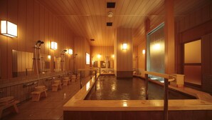 Een traditioneel Japans onsen met houten inrichting, meerdere warmwaterbaden en houten krukken.